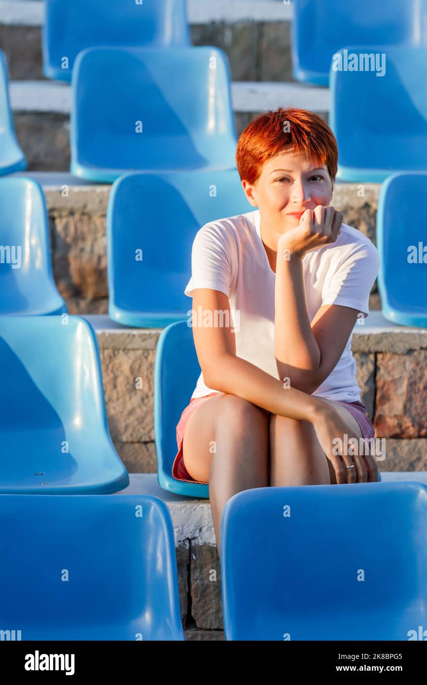 young-woman-with-short-red-hair-sits-relaxed-in-deserted-open-air