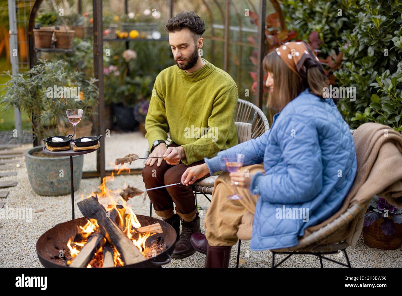 Young couple spending dinner time by the fire at backyard Stock Photo