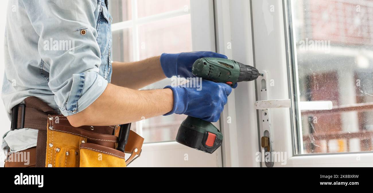 master with a screwdriver sets fittings on the window Stock Photo