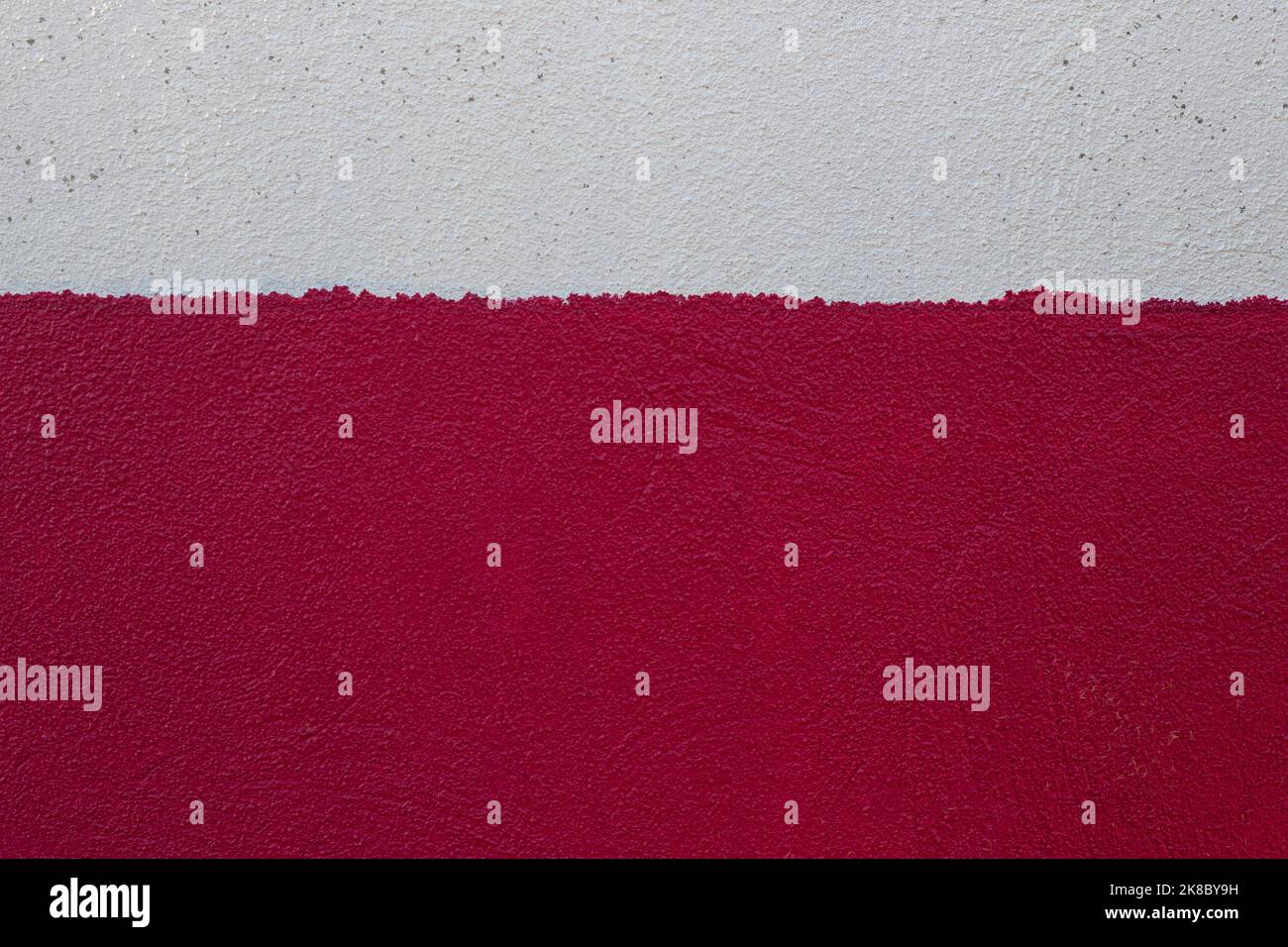 Old rough wall texture painted in two messy horizontal strips of white and red colors. Abstract background with empty space for text Stock Photo