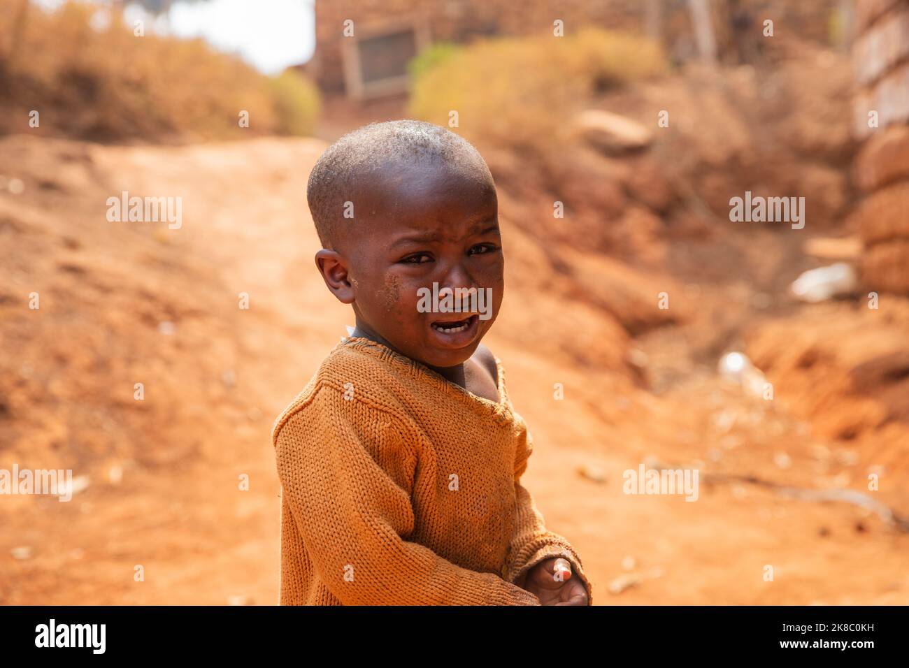 Portrait of a poor african child crying in the village, he wears dirty clothes Stock Photo
