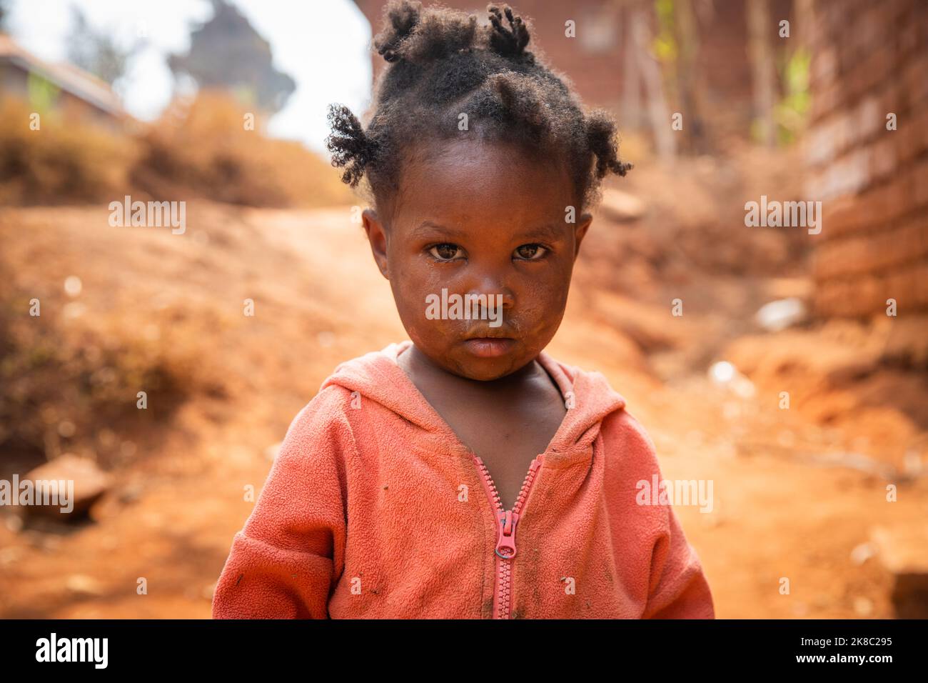 Poor little girl wearing dirty clothes in an African village, poverty and crisis concept Stock Photo