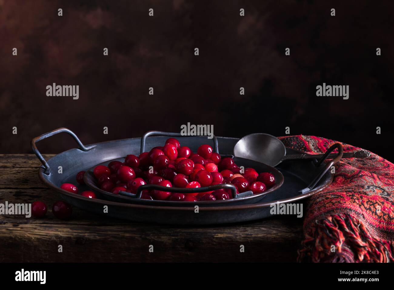 Still life with 2 rustic plates filled with fresh cranberries on an antique wooden table Stock Photo