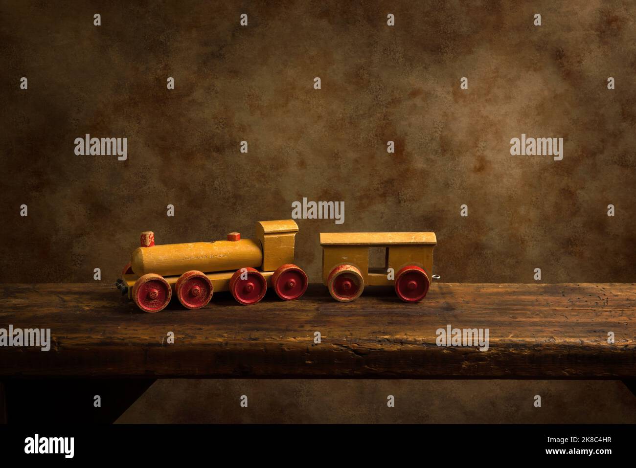 Cute old wooden train toy with red wheels on a rustic old wooden shelf. Stock Photo