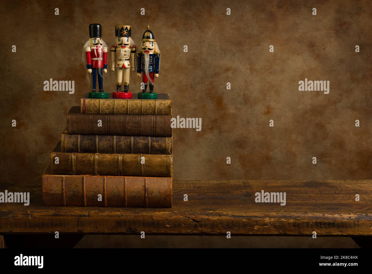 Three funny nutcracker puppets on old books on a rustic old wooden shelf. This is suitable for digital compositing. Stock Photo