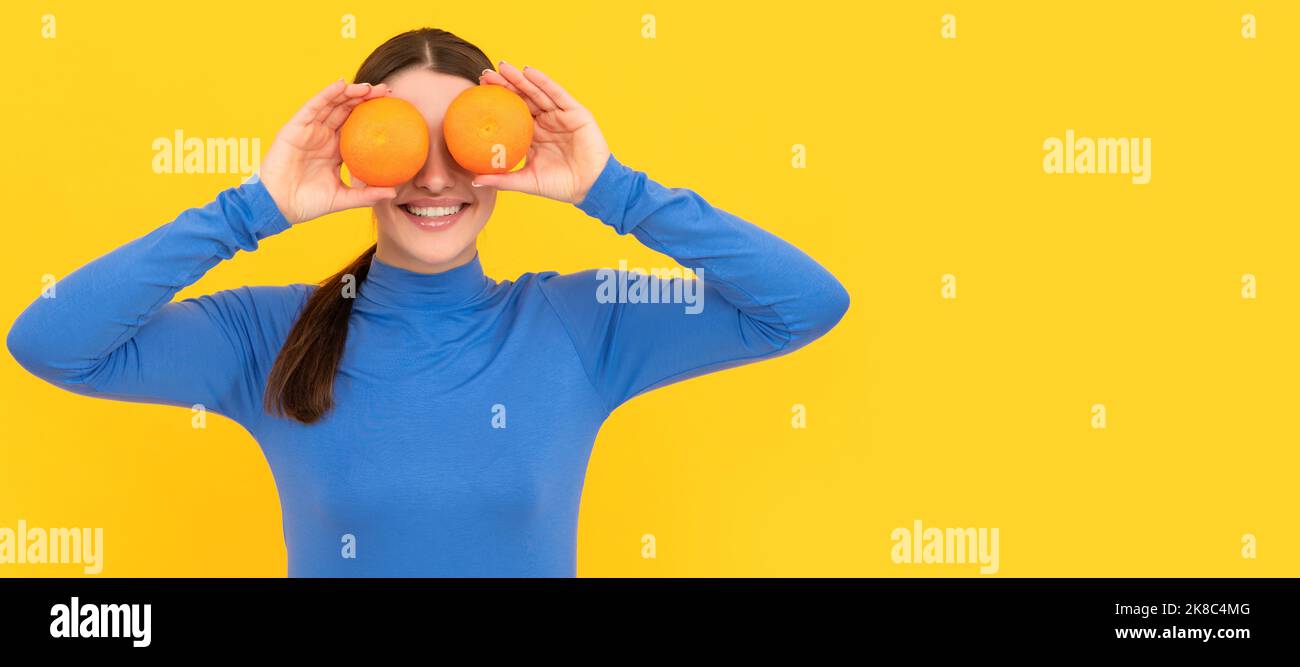 Woman isolated face portrait, banner with copy space. funny young woman holding orange citrus fruit on yellow background, vitamin. Stock Photo