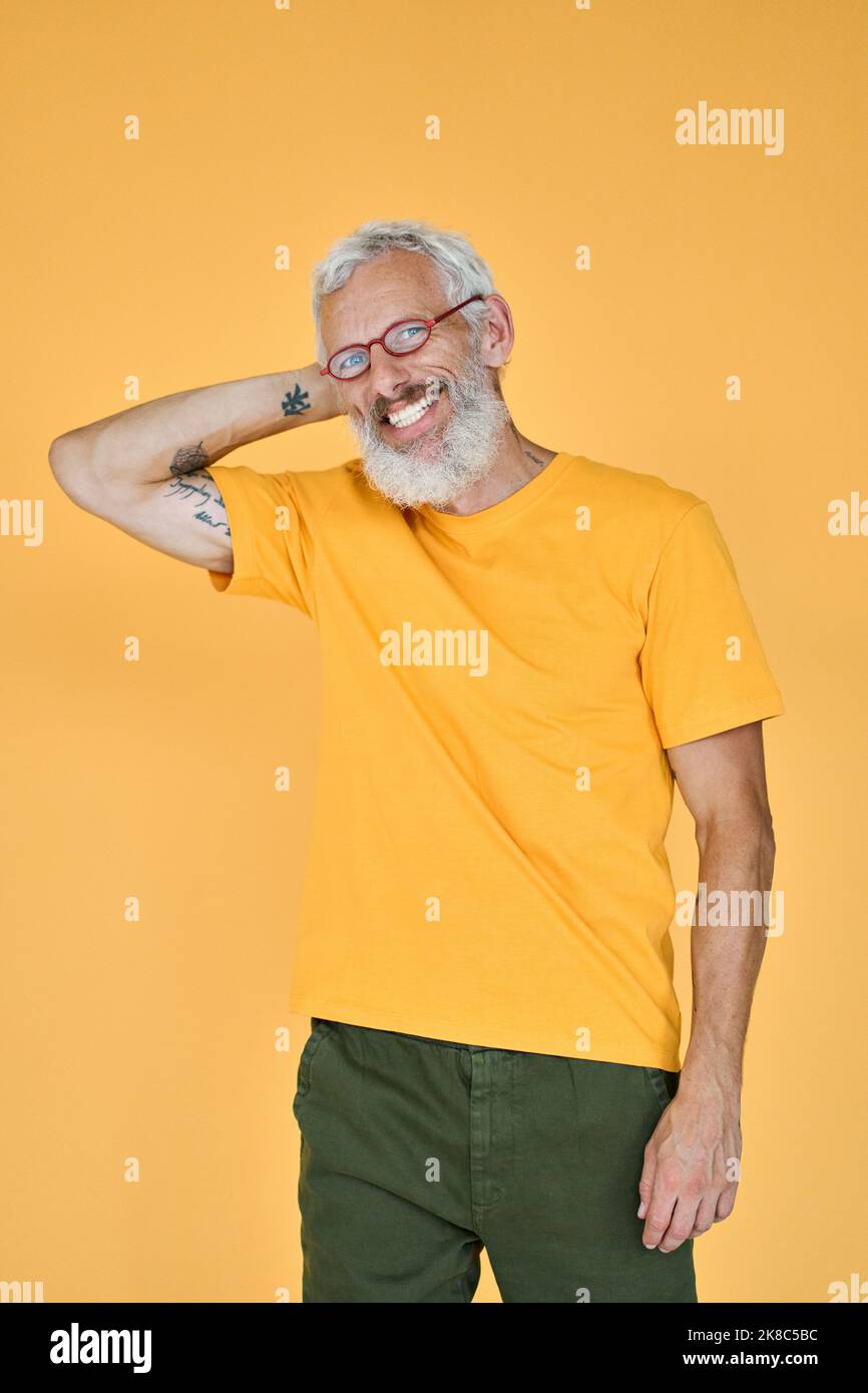 Smiling older bearded hipster man standing isolated on yellow background. Stock Photo