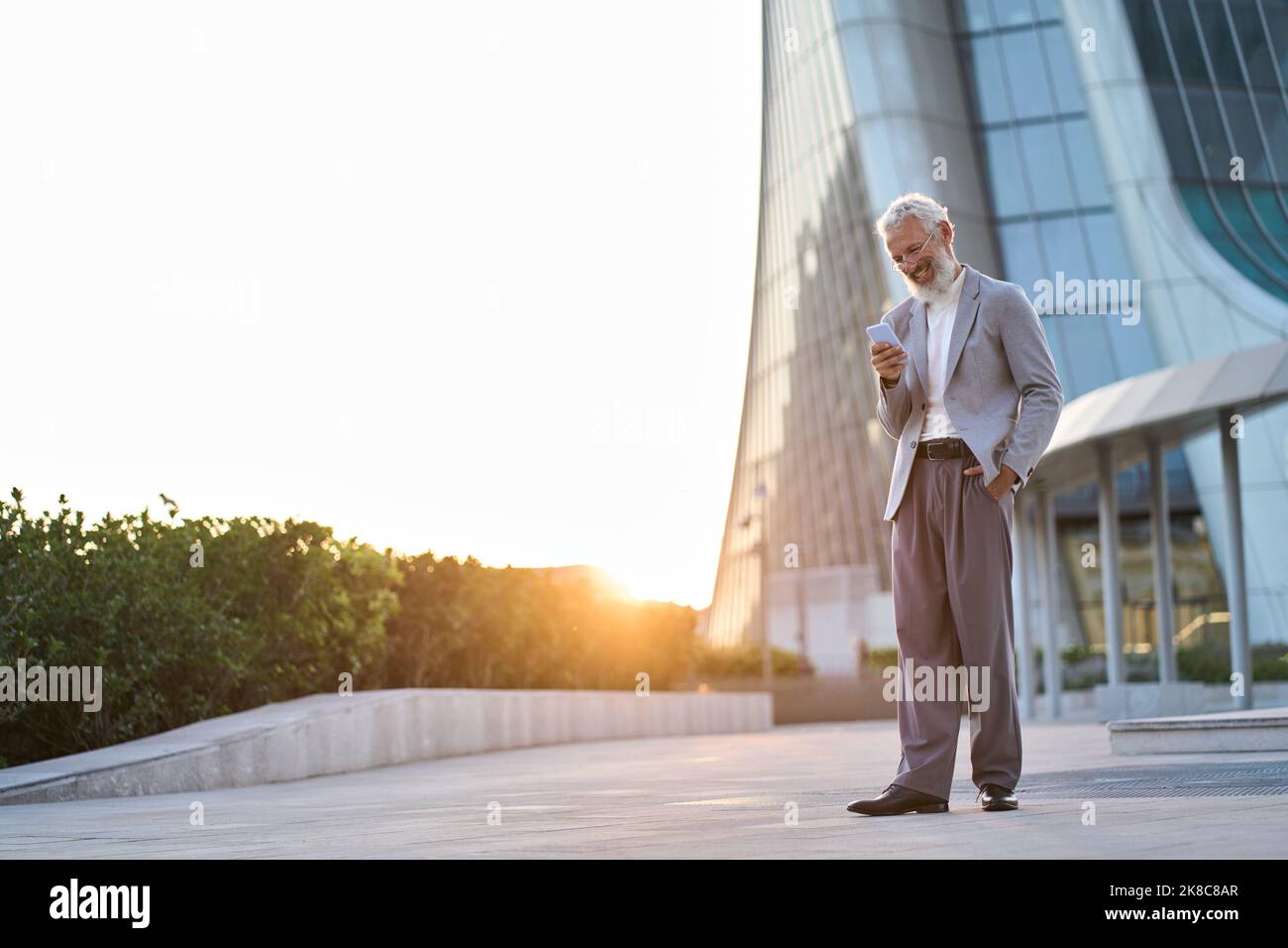 Happy old senior stylish business man holding using mobile phone in city. Stock Photo
