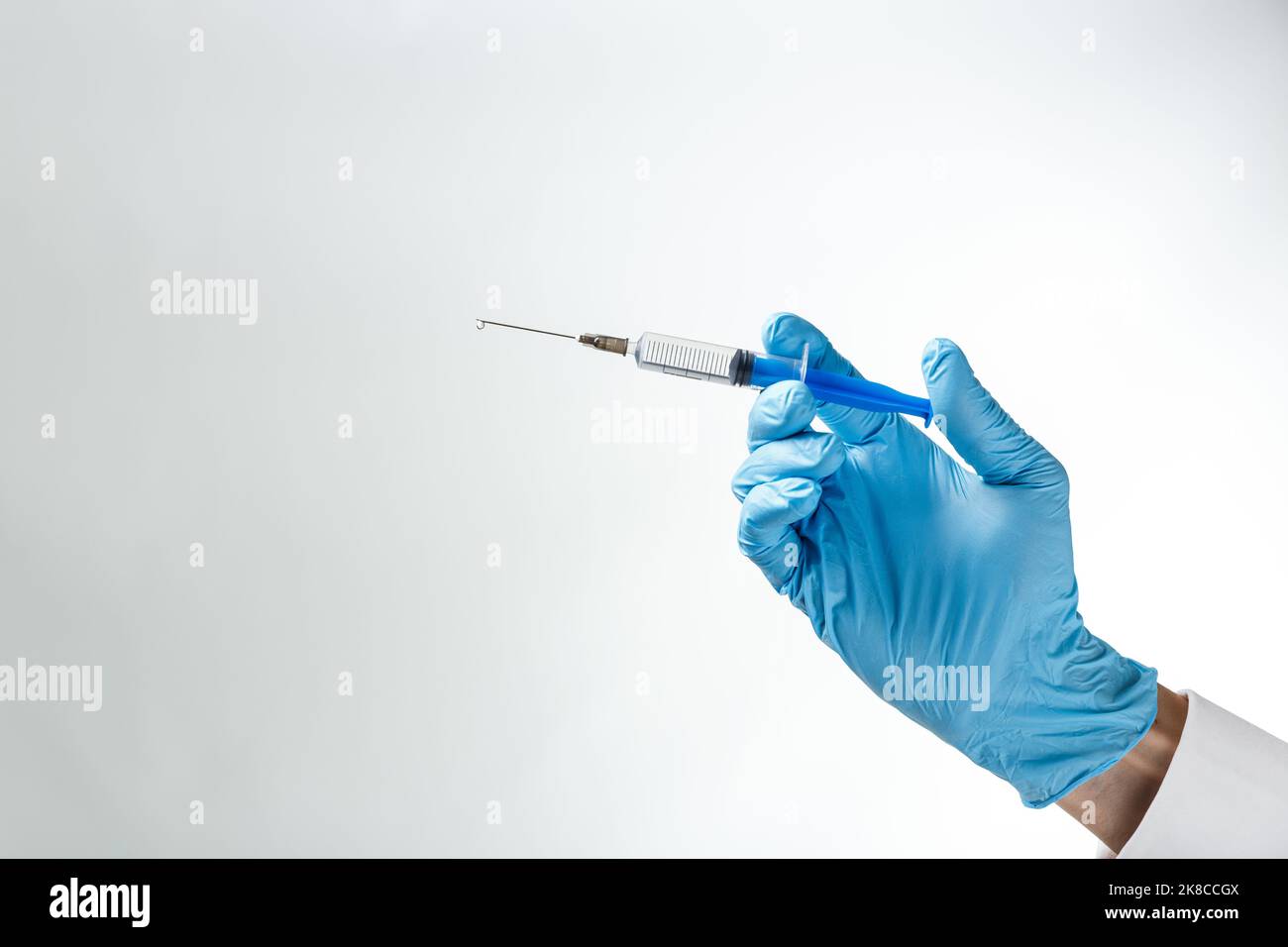 Syringe with a drop on a needle in hand in a blue rubber glove on a ...