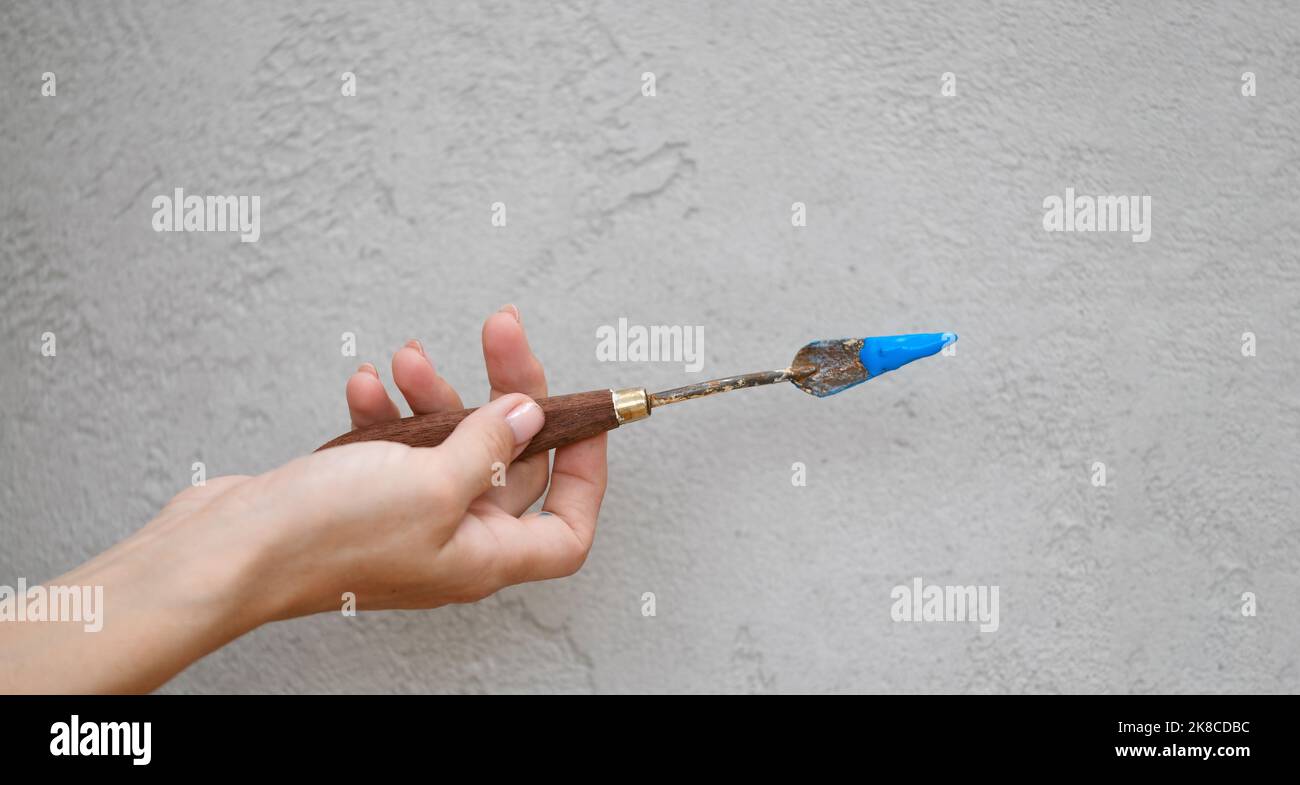 Spatulas for acrylic paints on grey wall background. Spatulas stained