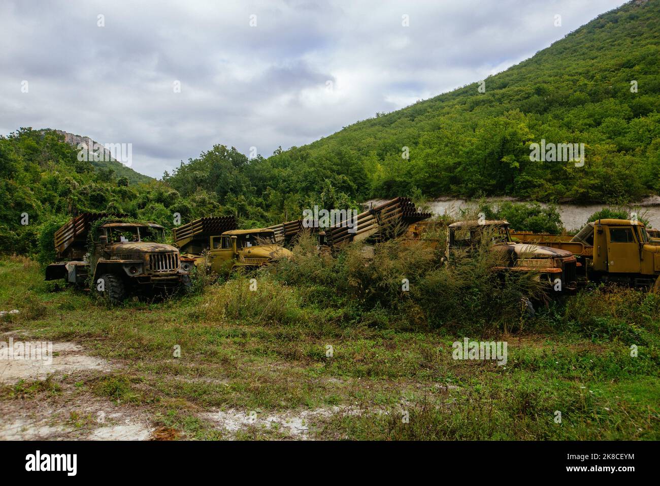Old abandoned rusty military trucks overgrown by plants Stock Photo