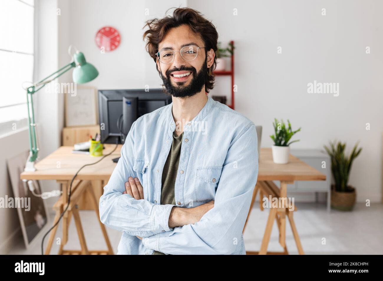 Smiling young creative businessman standing at modern workplace Stock Photo