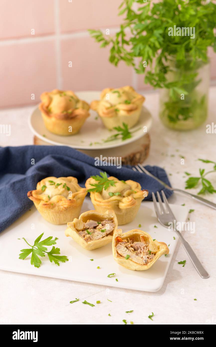Chicken pies and parsley leaves on white ceramic dishes in a kitchen