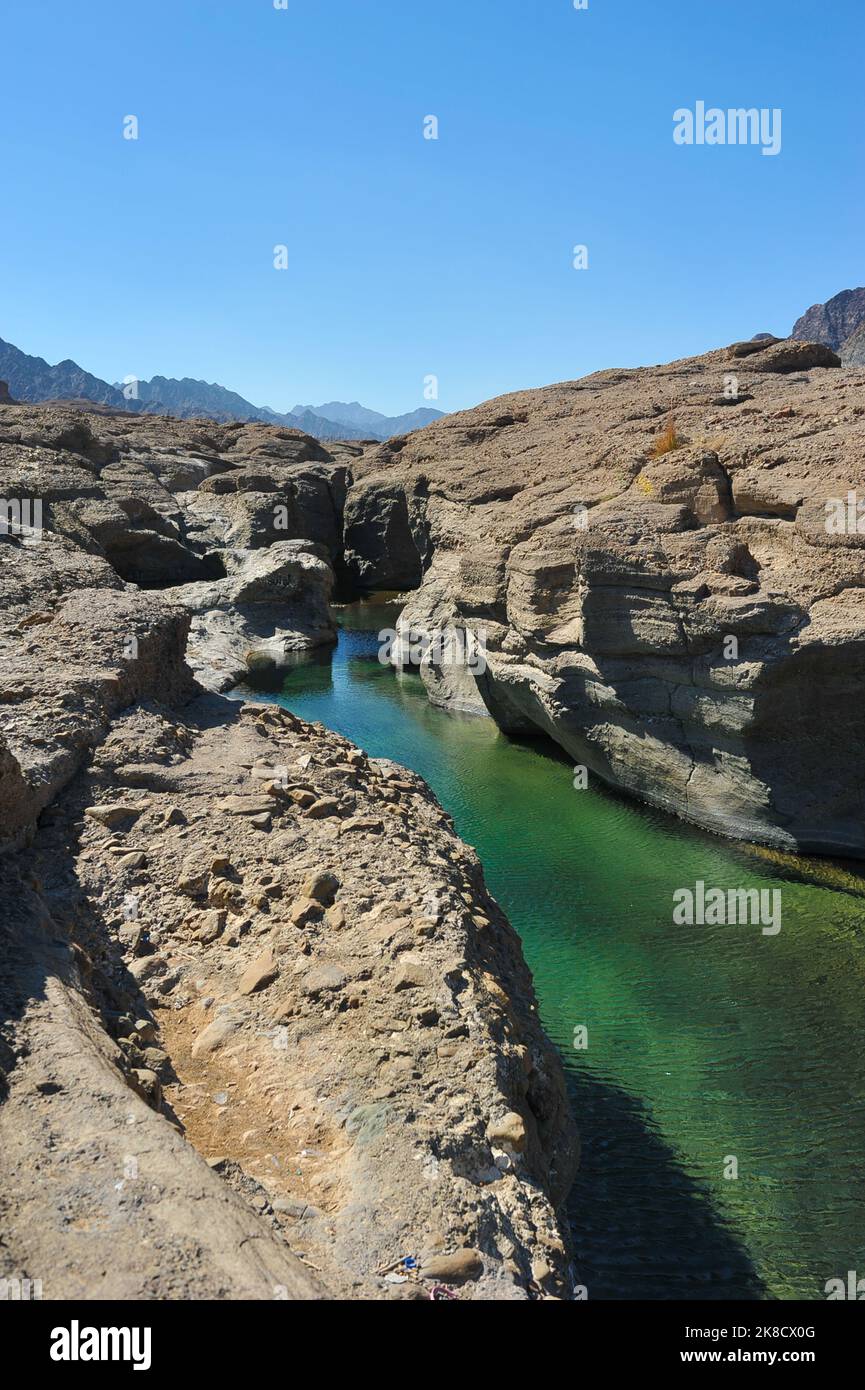 Fresh, clear rock pool in Hatta, an inland exclave of Dubai, UAE. Exotic Wadi Al Qahfi on a summer day. Rocky, rugged landscape with vibrant waters. Stock Photo