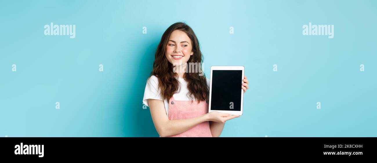 Image of happy young girl showing digital tablet screen and smiling ...