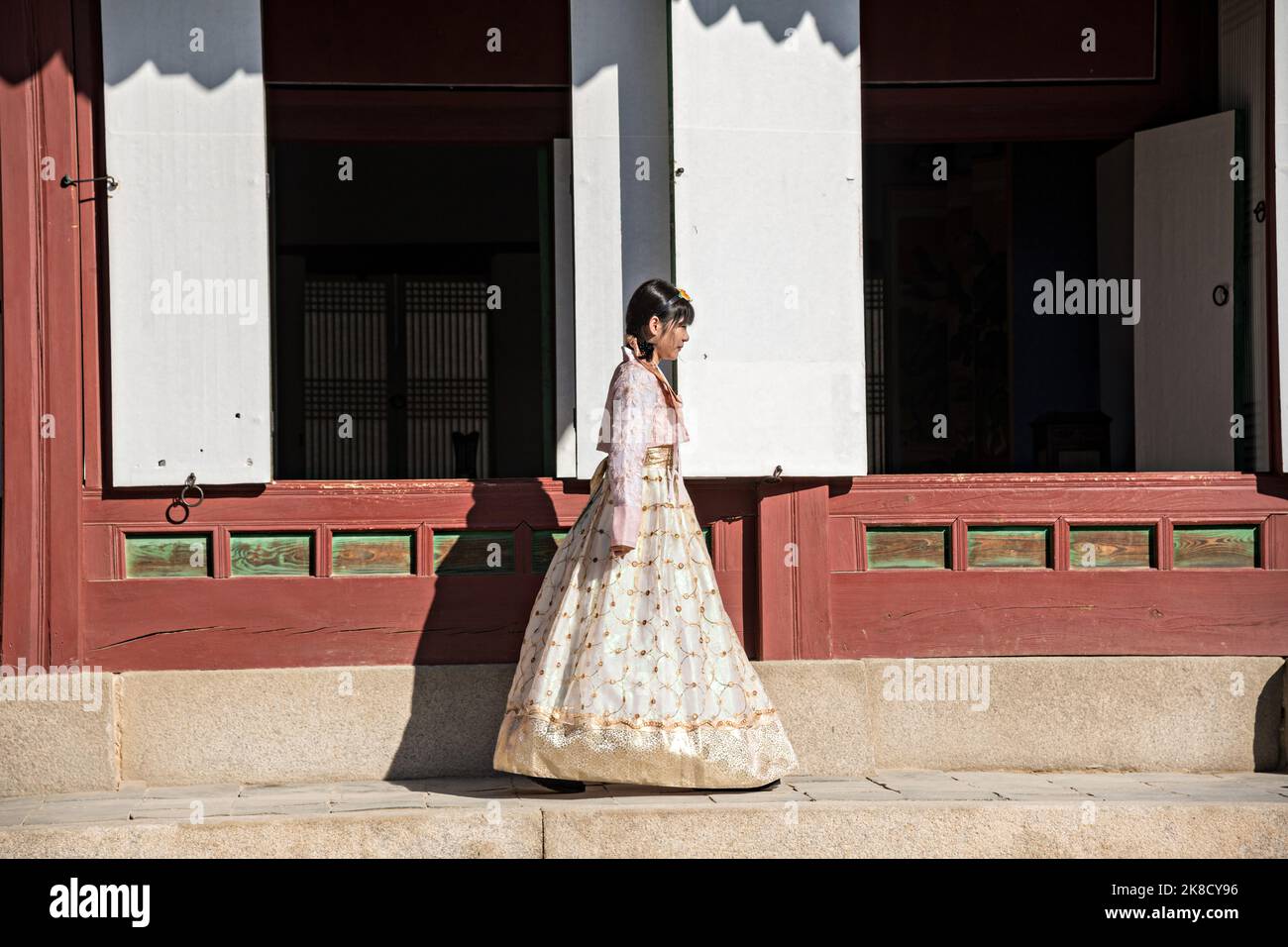 A Chinese tourist, dressed in traditional Korean costume walks through the Geunjeong-jeon or Throne Hall, at the Gyeongbokgung Palace in Seoul, South Korea. Stock Photo