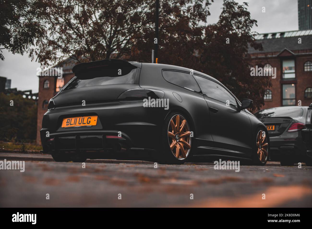 A Modified Satin Black Wrapped 2011 Volkswagen Scirocco R Hatchback With Gold Aftermarket Bentley Alloy Wheels With Aftermarket Bodykit And Air Suspen Stock Photo