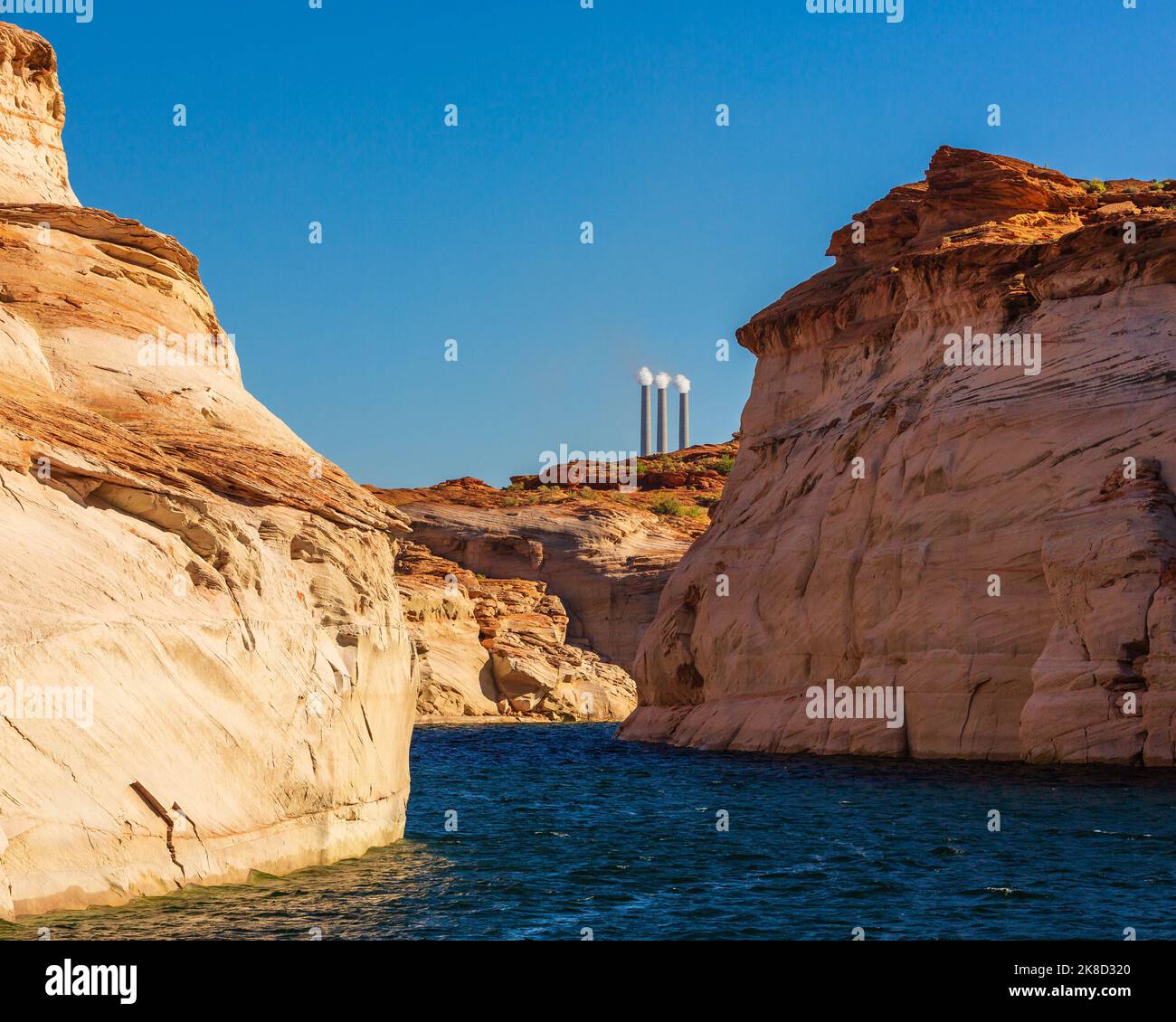 Smoke stacks from the Navajo Generating Station rise up behind formations of Antelope Canyon in Lake Powel. Stock Photo