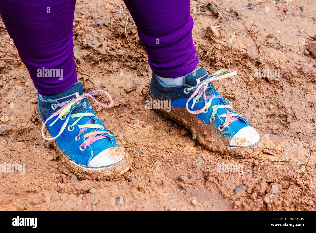 A young girl with colorful muddy shoes from playing outside. Stock Photo