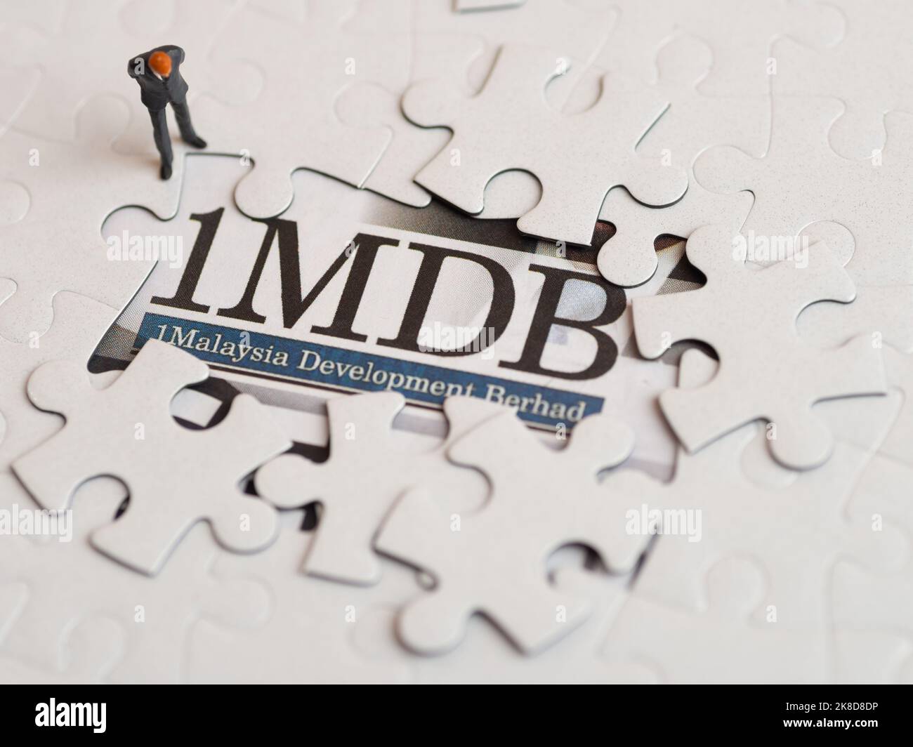 Illustrative editorial of 1MDB scandal concept - 1Malaysia Development Berhad criminal case-miniature figurine of a businessman looking at a jigsaw pu Stock Photo