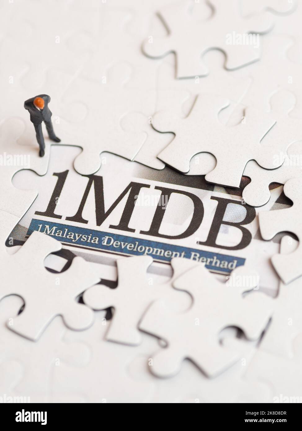 Illustrative editorial of 1MDB scandal concept - 1Malaysia Development Berhad criminal case-miniature figurine of a businessman looking at a jigsaw pu Stock Photo