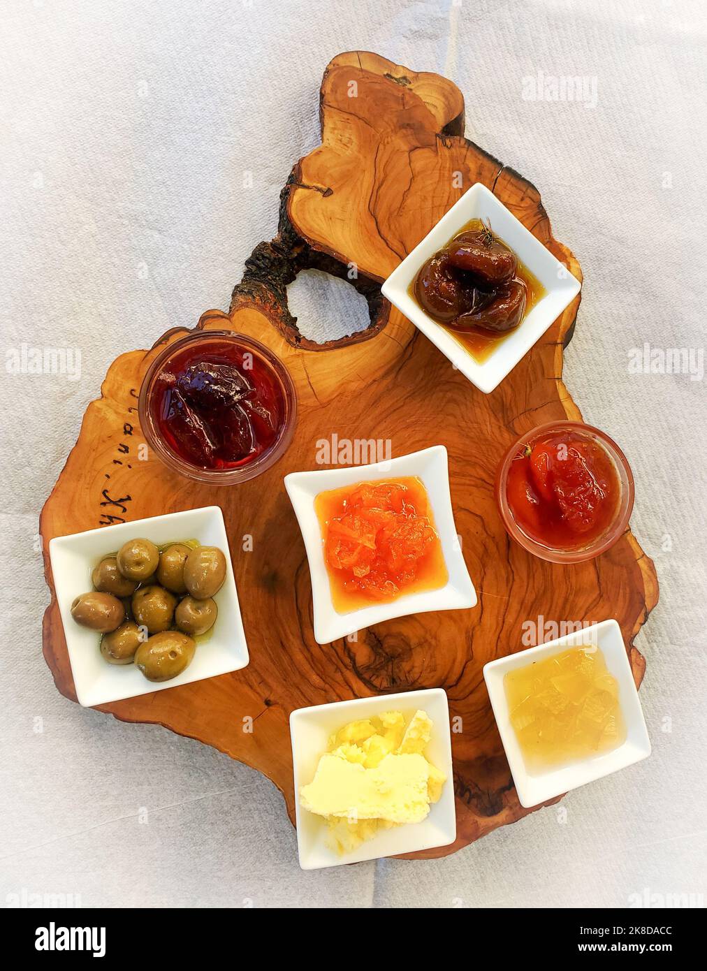 Wood plank serving platter with seven small dishes of condiments with