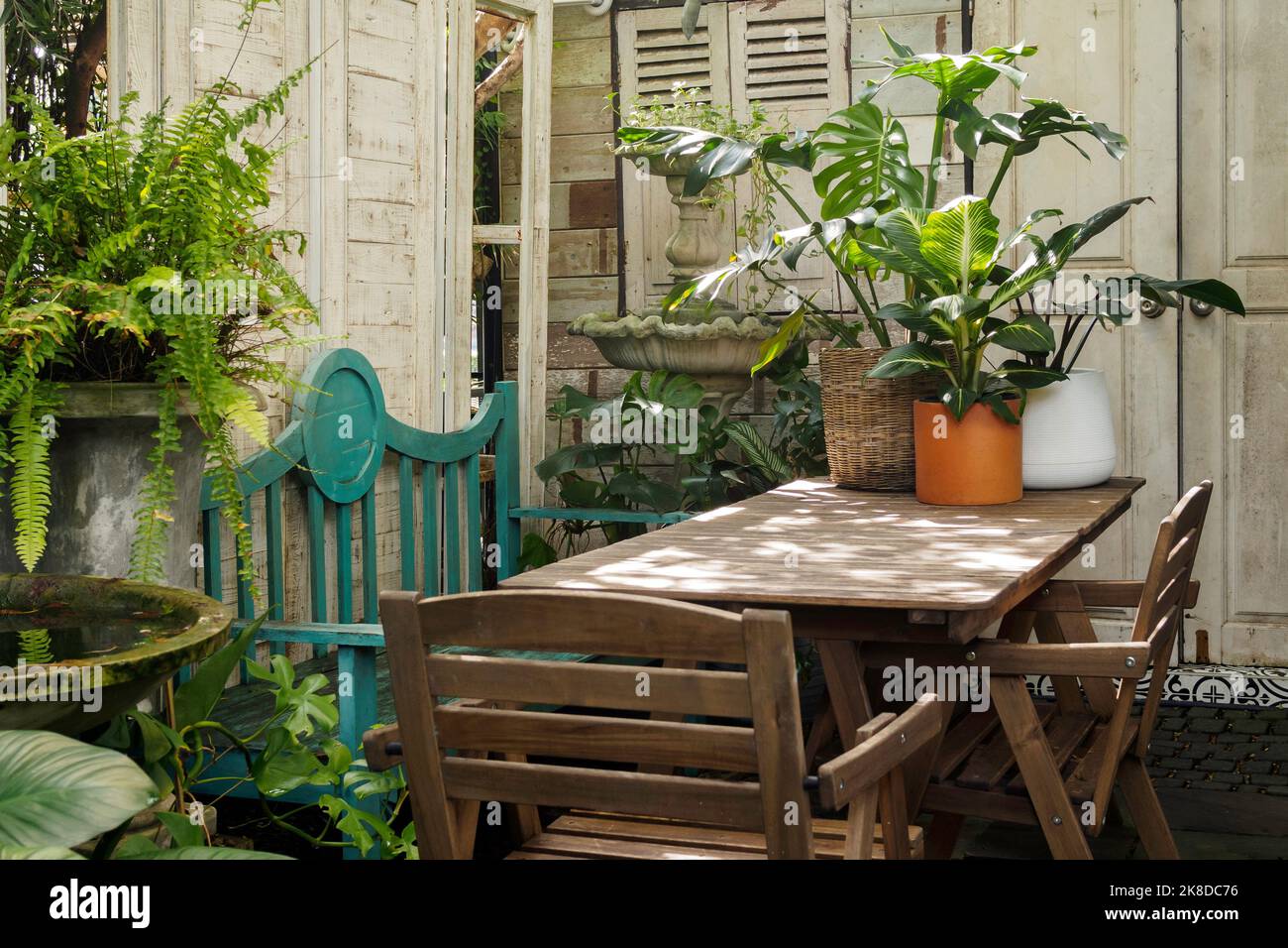 outdoor vintage home garden decoration. Wooden table and chair for lunch outside in the garden with warm sunlight at beautiful morning in summer. Stock Photo