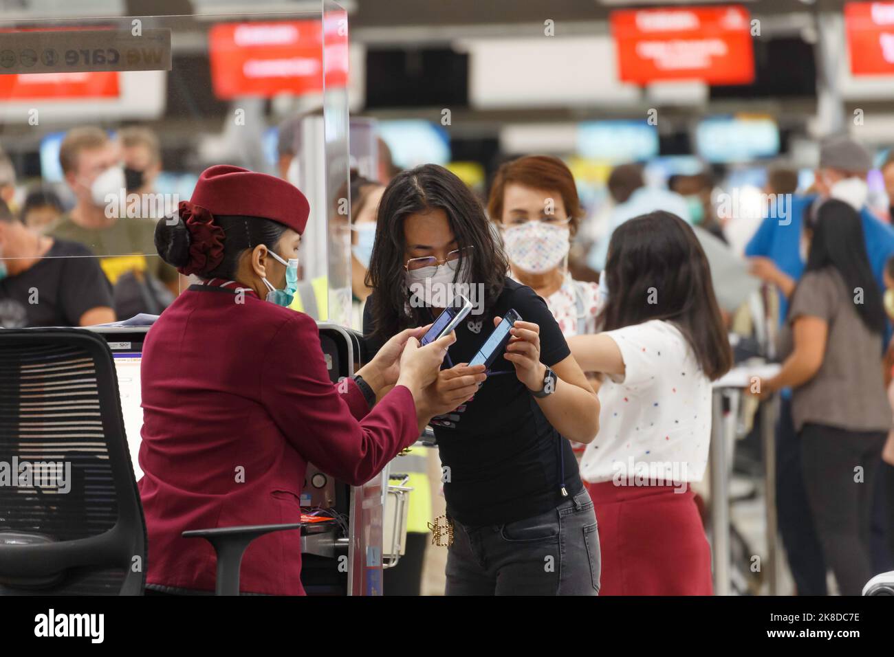Bangkok, Thailand - October 26, 2022 : asian passenger using smart phone to check in at airline counter in suvarnabhumi airport, Thailand. Stock Photo