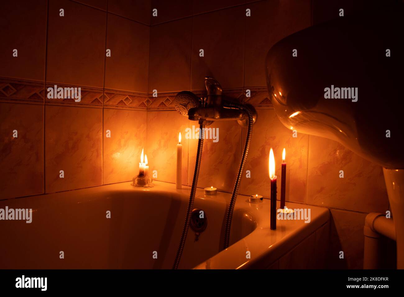 Candles in the bathroom in a dark apartment in Ukraine, Ukraine without electricity due to the war, turned off the light Stock Photo