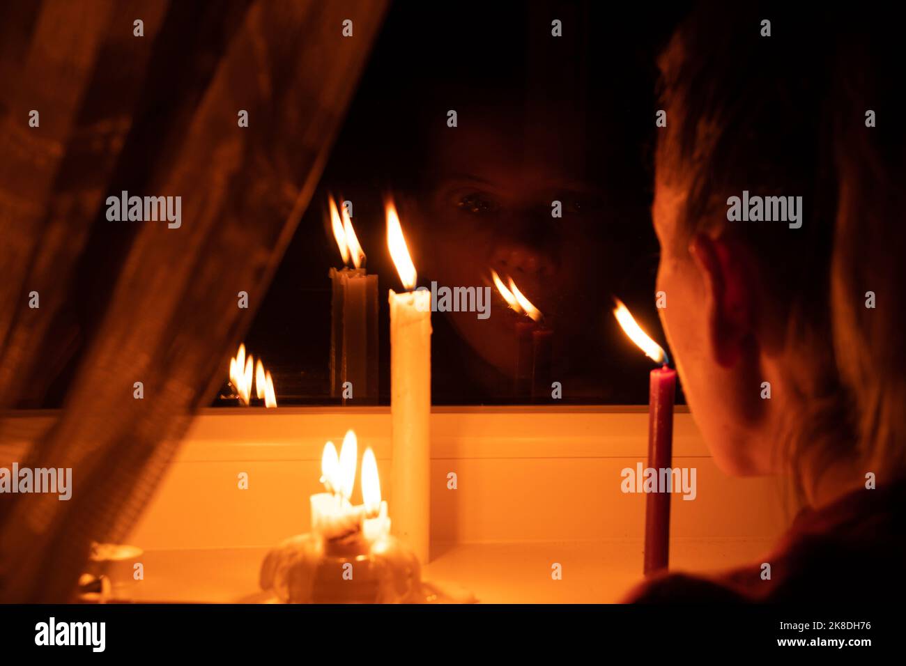 The girl's face put candles on the window in an apartment in Ukraine