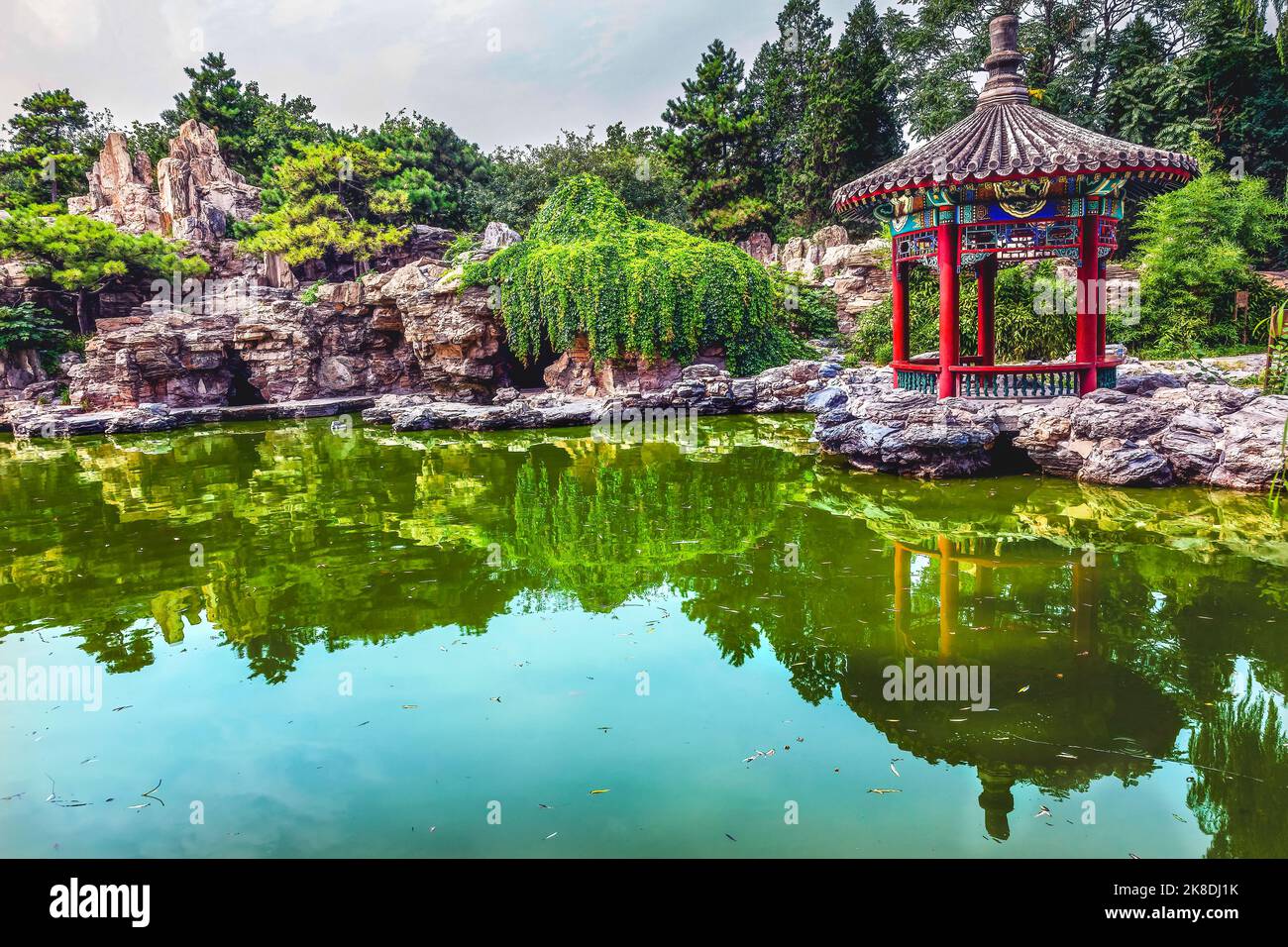 Red Pavilion Rock Garden Water Pond Reflection Temple of Sun City Park, Beijing, China Willow Green Trees Stock Photo
