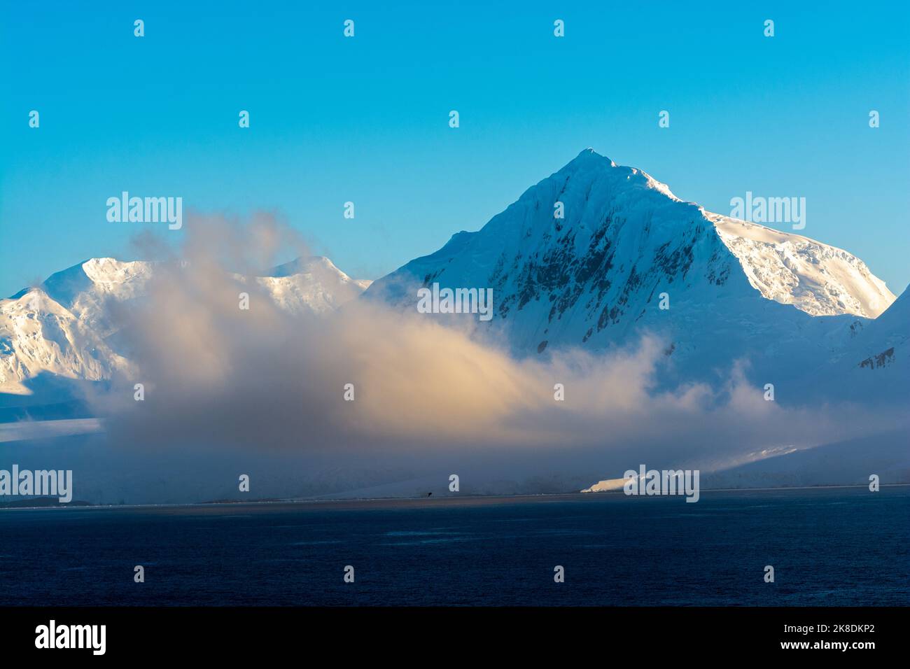 early morning sun lights up mt. william (r) on anvers island. antarctic