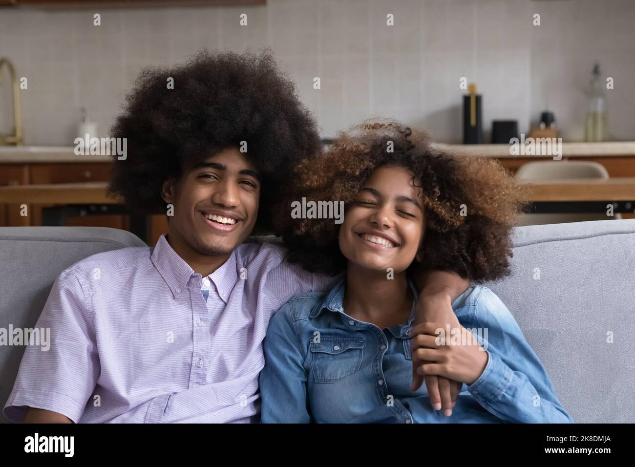 African teenage couple sit on sofa smile look at camera Stock Photo