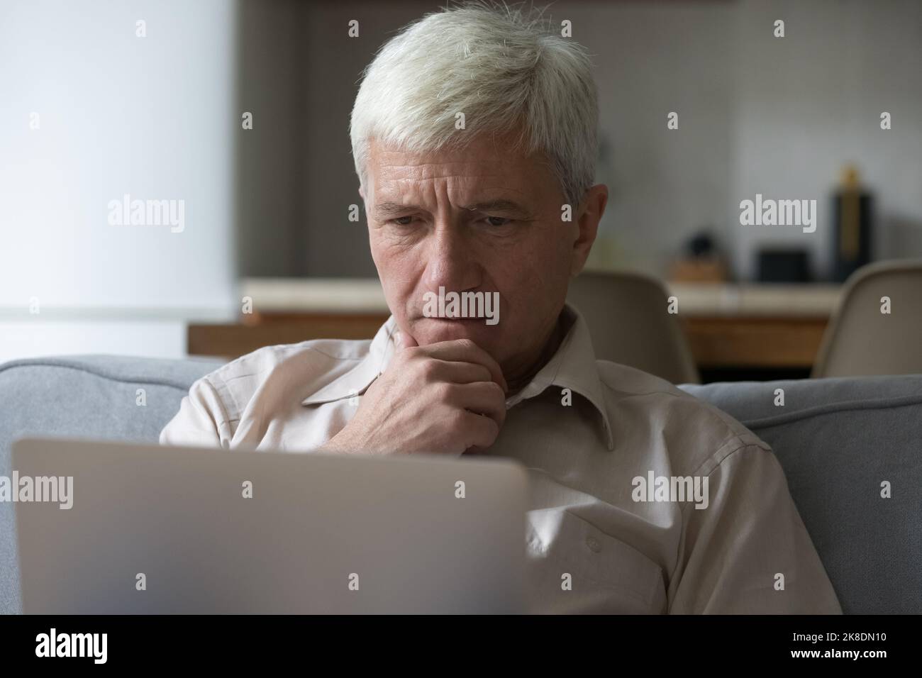 Thoughtful grey-haired mature man learning laptop app or software Stock Photo