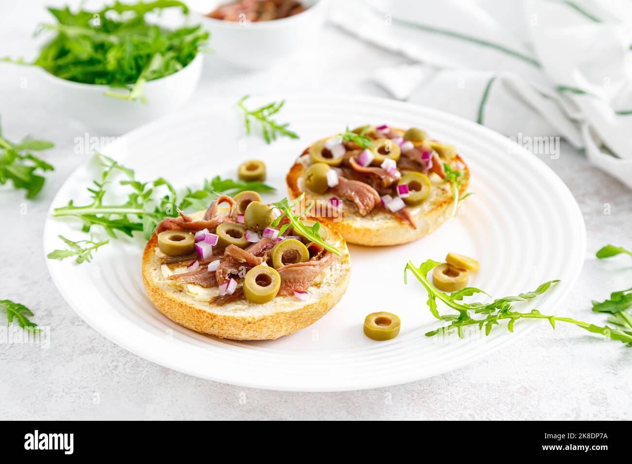 Anchovy toasts with olives and arugula Stock Photo