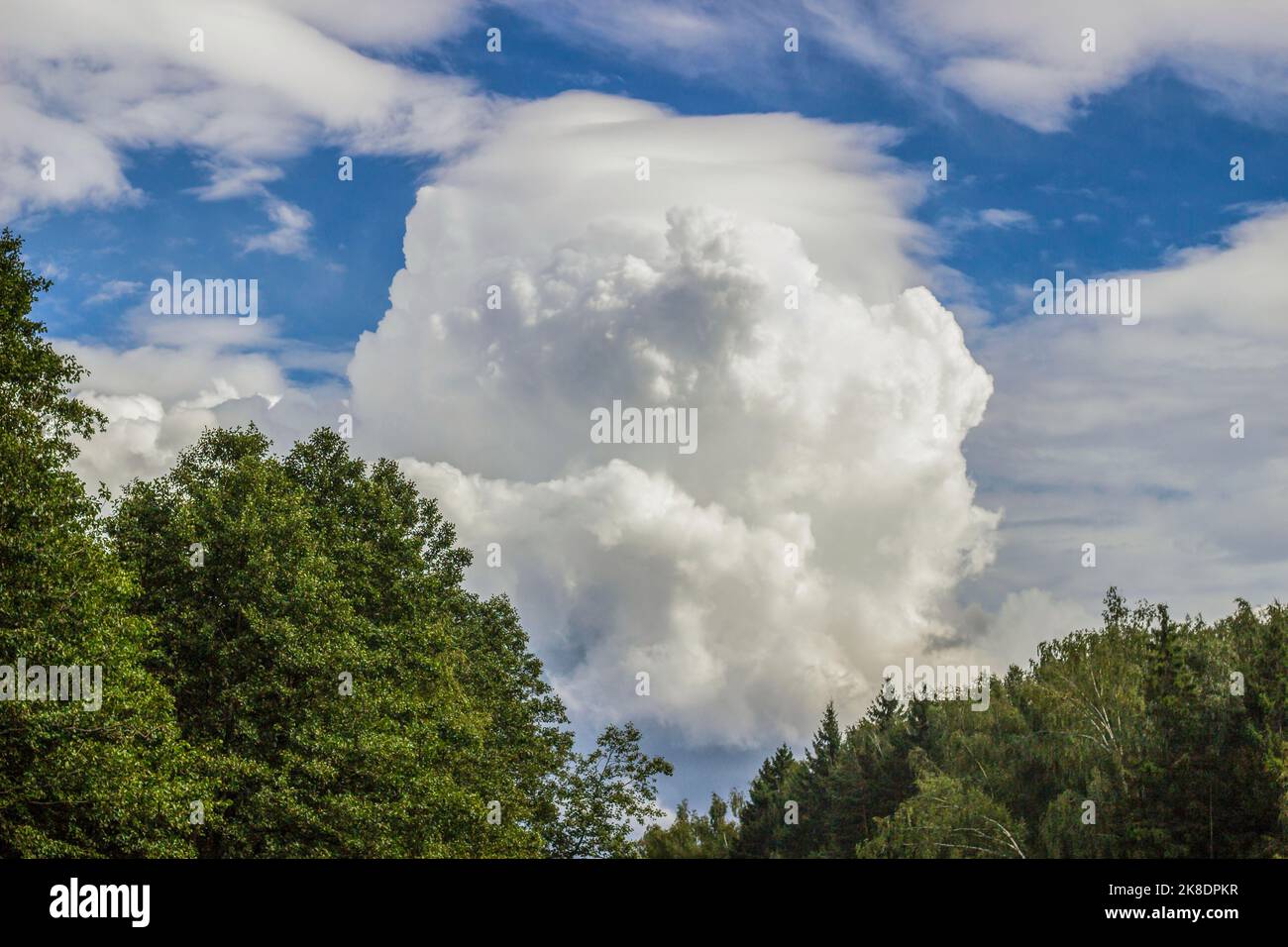 A cumulus cloud floats across the sky like a big mountain. A thunderous front is approaching. Beautiful heavenly phenomenon. Aerial landscape. Stock Photo