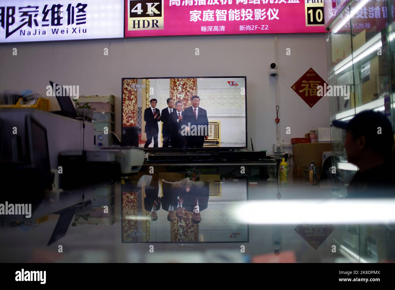 A man watches a television showing footage of Chinese President Xi Jinping and other members of the new Politburo Standing Committee meeting the media following the 20th National Congress of the Communist Party of China, at a store in Shanghai, China October 23, 2022. REUTERS/Aly Song Stock Photo