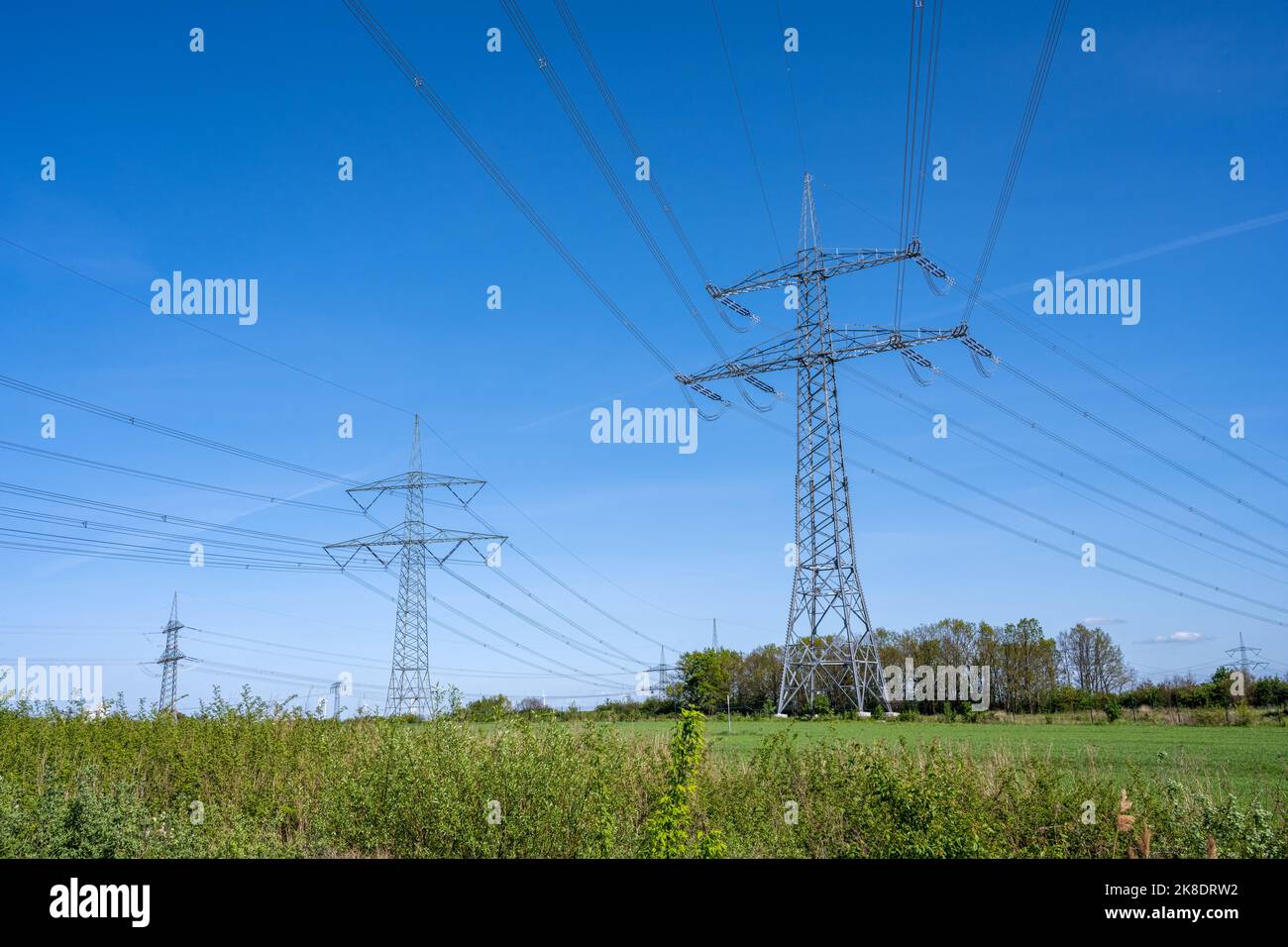 Electricity pylons and power lines in front of a blue sky seen in Germany Stock Photo