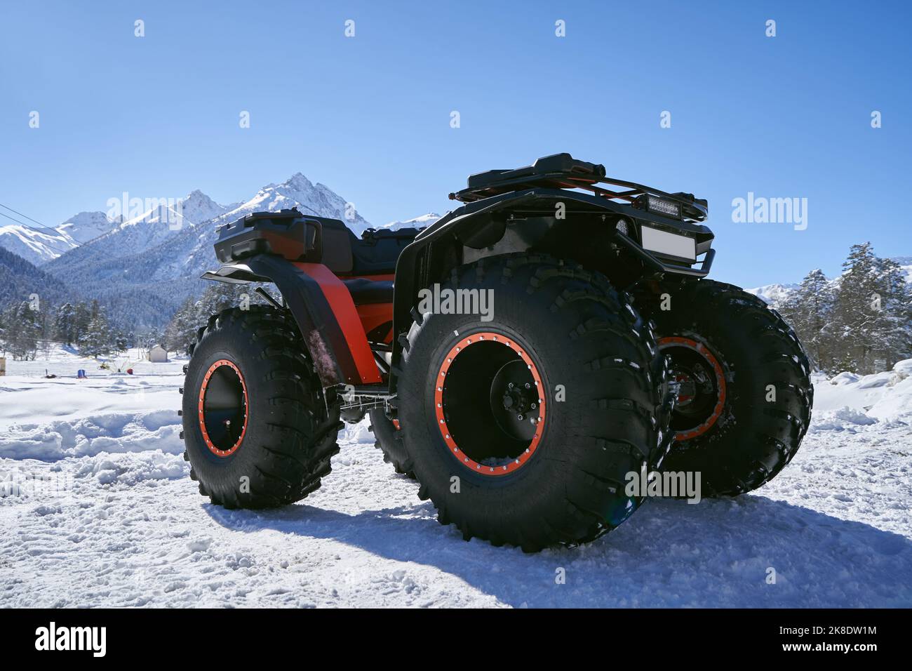 Quad bike with big wheels on the snow in mountains. Stock Photo