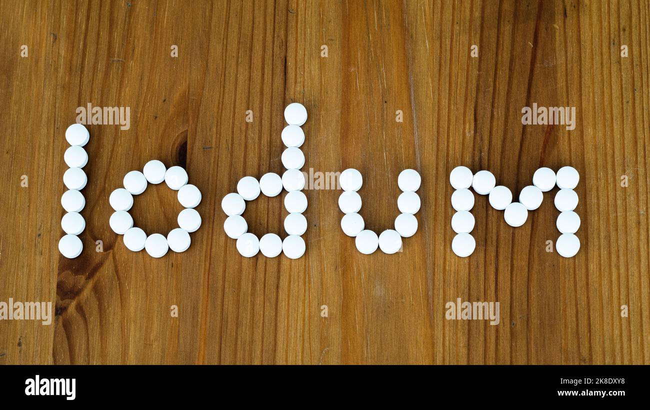 Iodum iodine pills on wooden background. Thyroid gland cancer concept