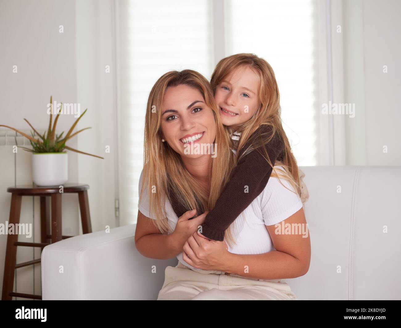 Young beautiful mother playing with daughter in livingroom Stock Photo