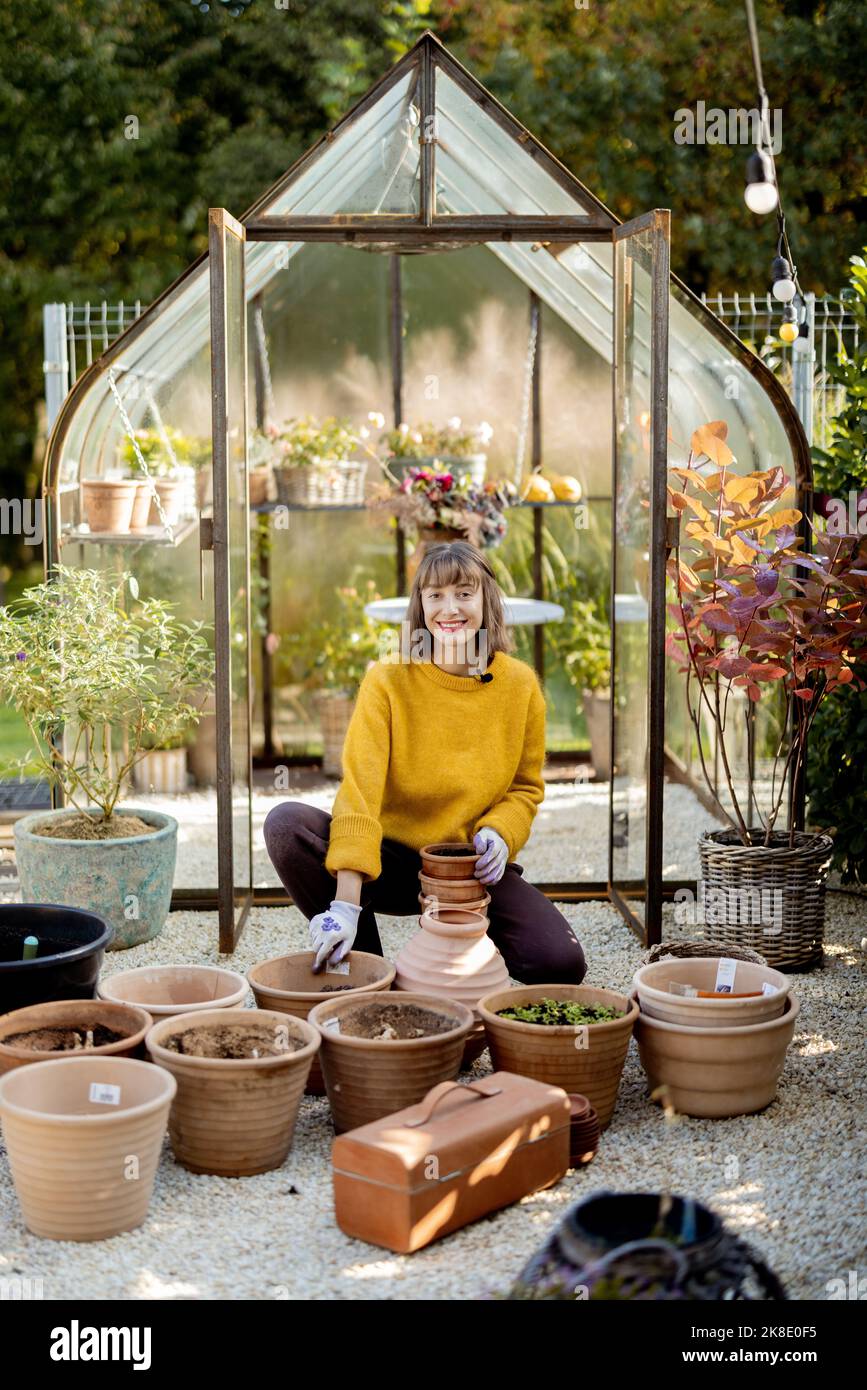 Woman planting flowers in jugs at garden Stock Photo - Alamy