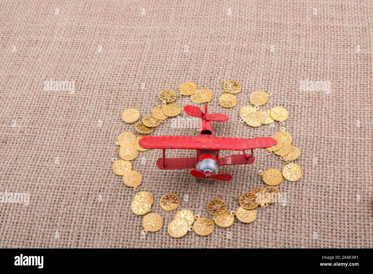 Fake gold coins around the retro model airplane Stock Photo