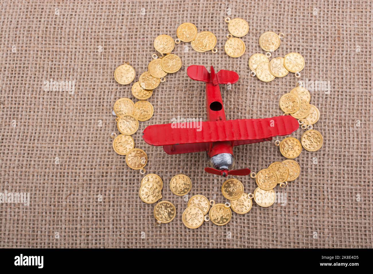 Fake gold coins around the retro model airplane Stock Photo