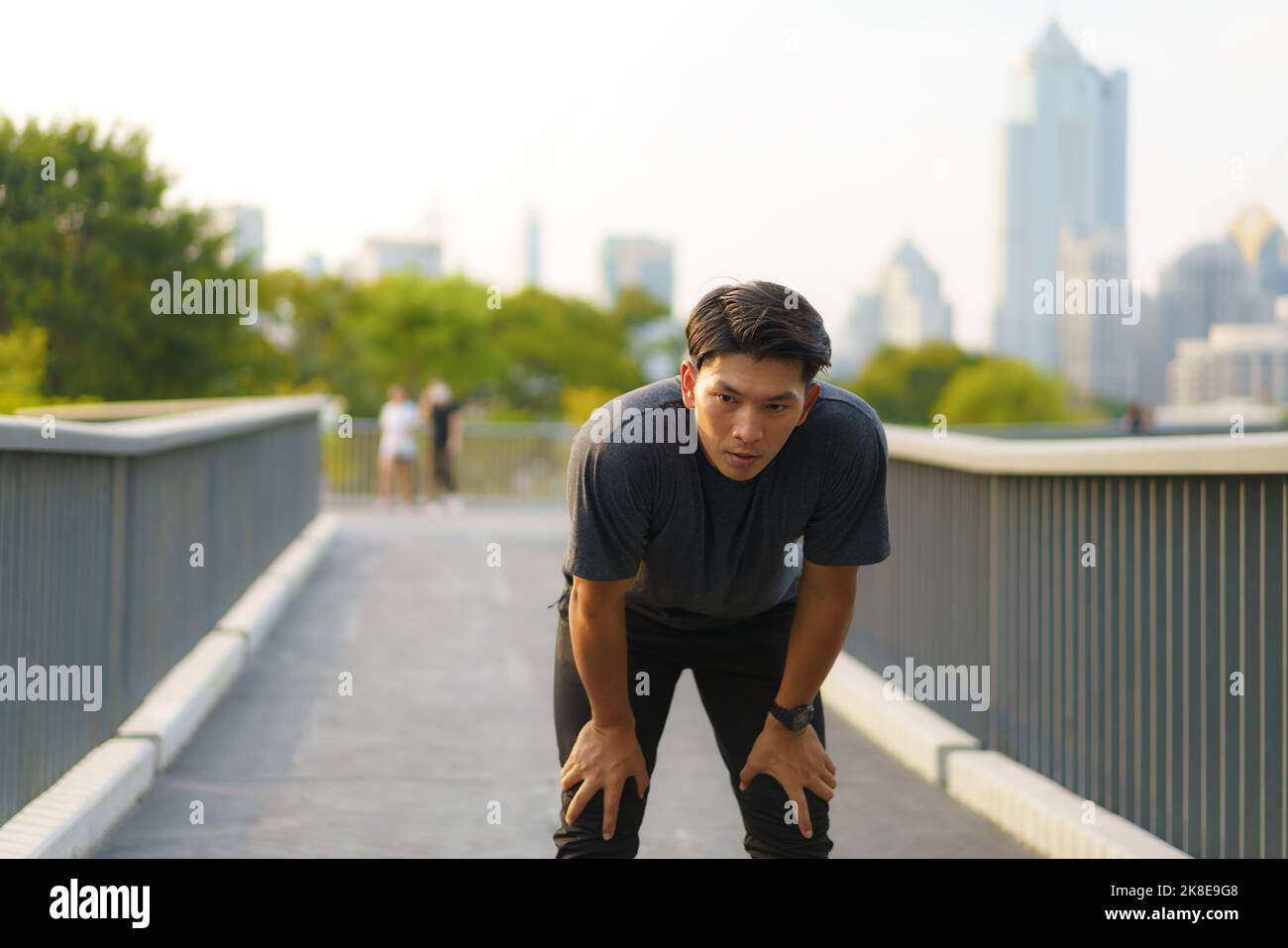 Asian tired man exhausted after an extreme exercise activity, running at the city park in eveing Stock Photo