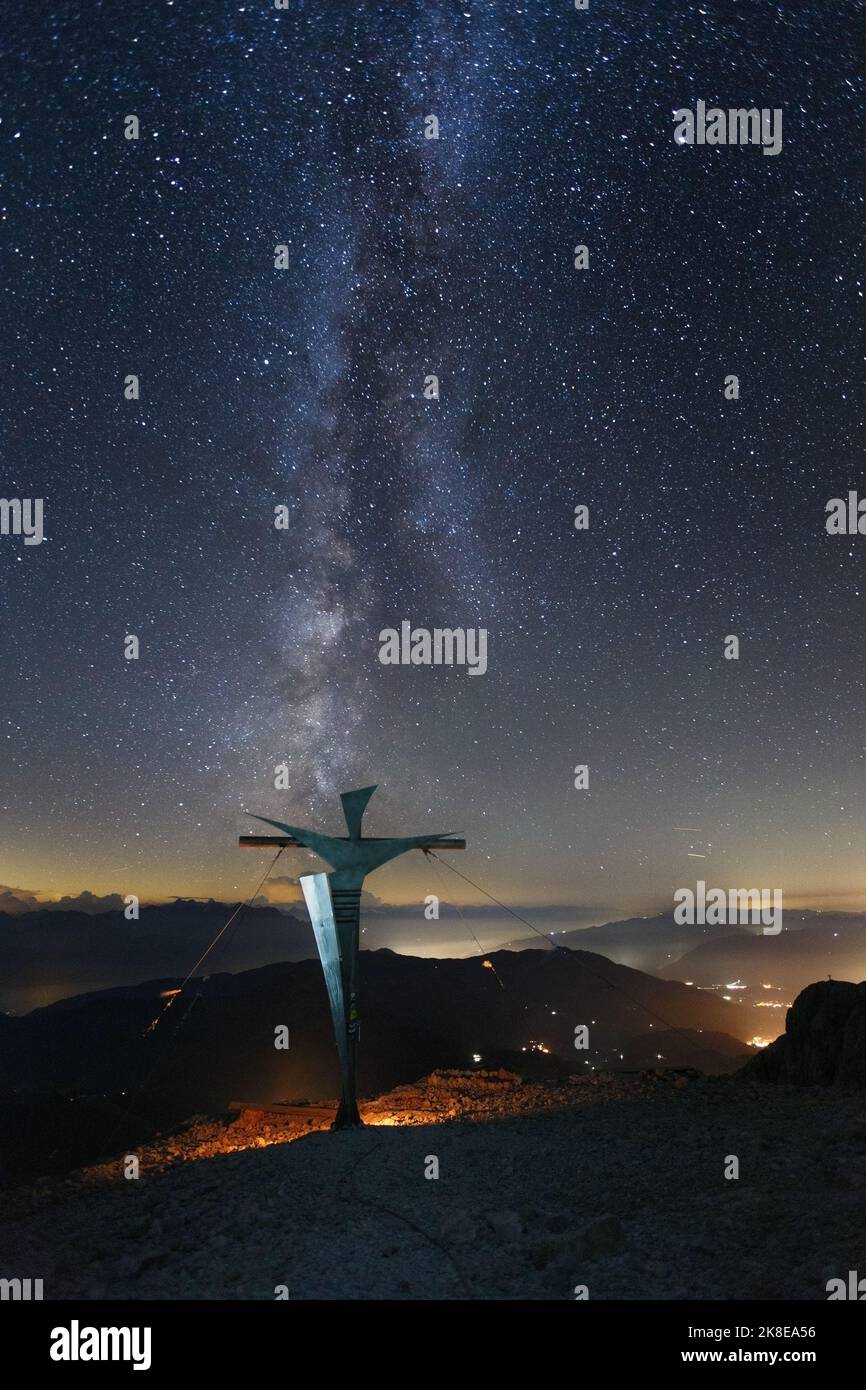 Night landscape with starry sky, milky way. Summit cross of Hochkönig mountain peak. Austria. Eastern Alps. Europe. Stock Photo