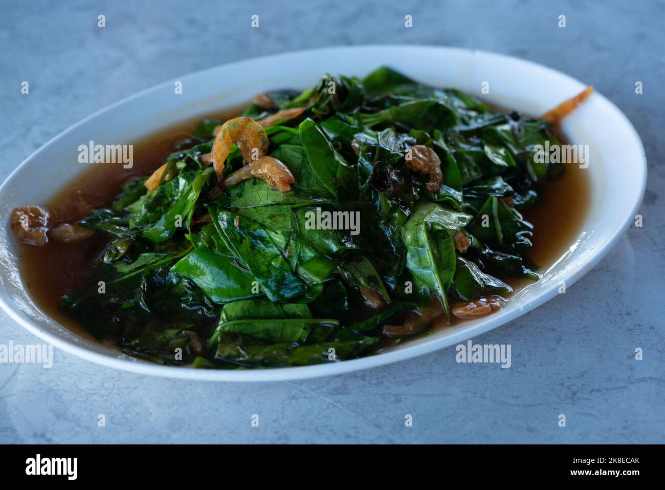 A plate of delicious stir-fried malindjo leaves with dried shrimp on the table. Stock Photo