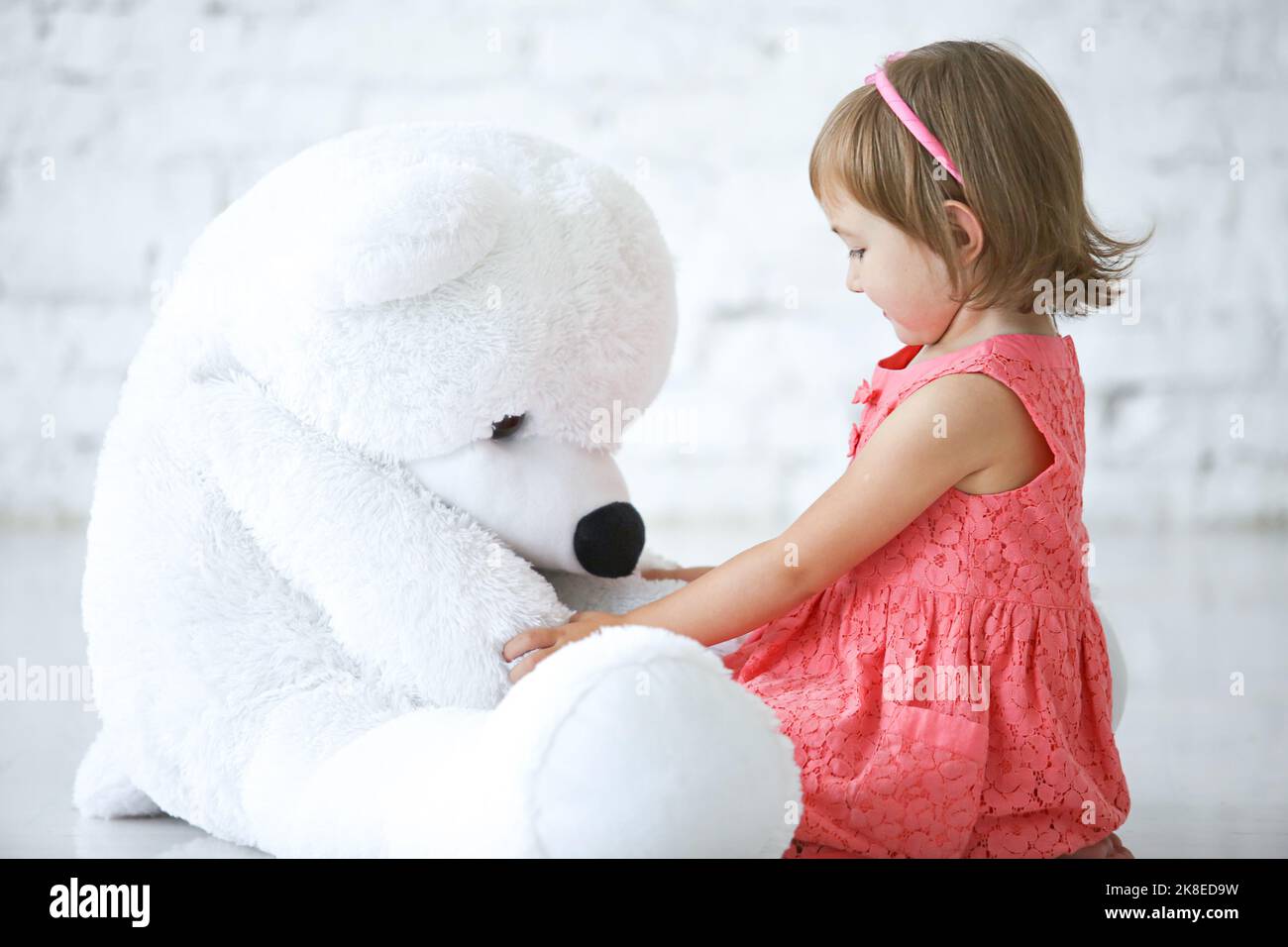 A little girl playying with big soft bear toy  in the room Stock Photo