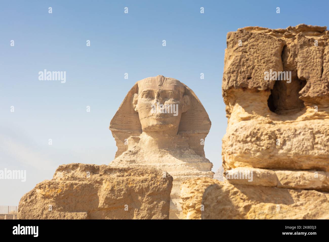 Egyptian Great Sphinx full body portrait with head, feet with all pyramids of Menkaure, Khafre, Khufu in background on a clear, blue sky day in Giza Stock Photo