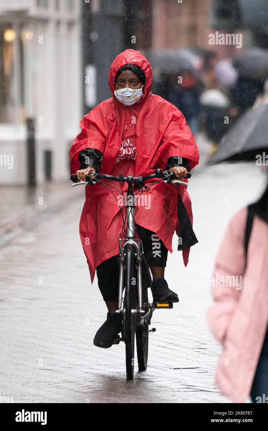 A woman cycles through Cambridge in heavy rain, as a yellow weather warning is in place across much of England and parts of Wales until 5am on Monday. Picture date: Sunday October 23, 2022. Stock Photo
